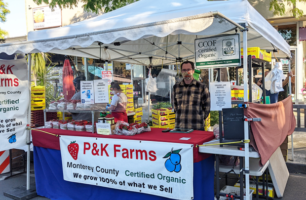 Worker stands behind booth full of berries.