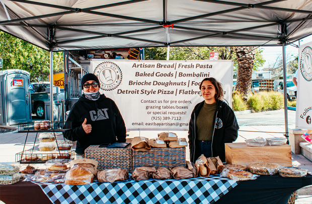 Picture of smiling producers behind table filled with goods