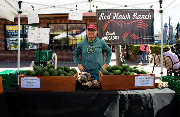 Producer smiling with hands on hips at stall in the farmers' market