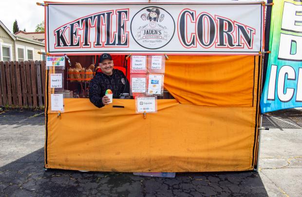 Photo of owner of Jaden's Kettle Corn handing snow cone out the window