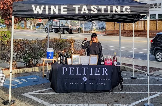 Seller holds up wine at the Peltier Wine booth at the Danville Farmers' Market