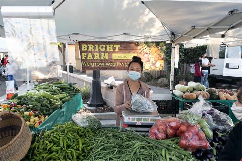 Bright Farm vendor behind table with various produce on display