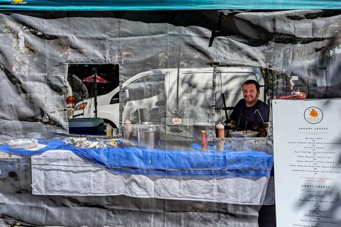A man pokes his head out of netting at the Brittany Crepes stall at the Concord Farmers' Market