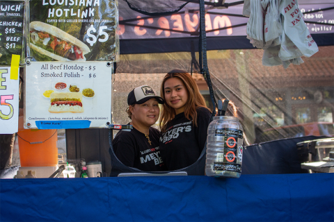 Two woman who own Meyer's BBQ looking through the window of their stall at the Concord Farmers' Market