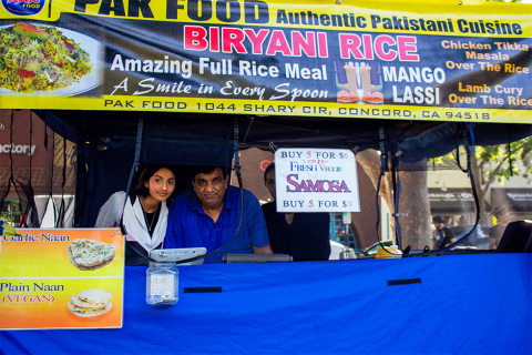 The father and daughter owners of Pak Food peeking through the window of their tent at Concord Thursday Farmers' Market
