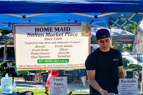 A man at the farmers' market in front of the Home Maid Ravioli booth