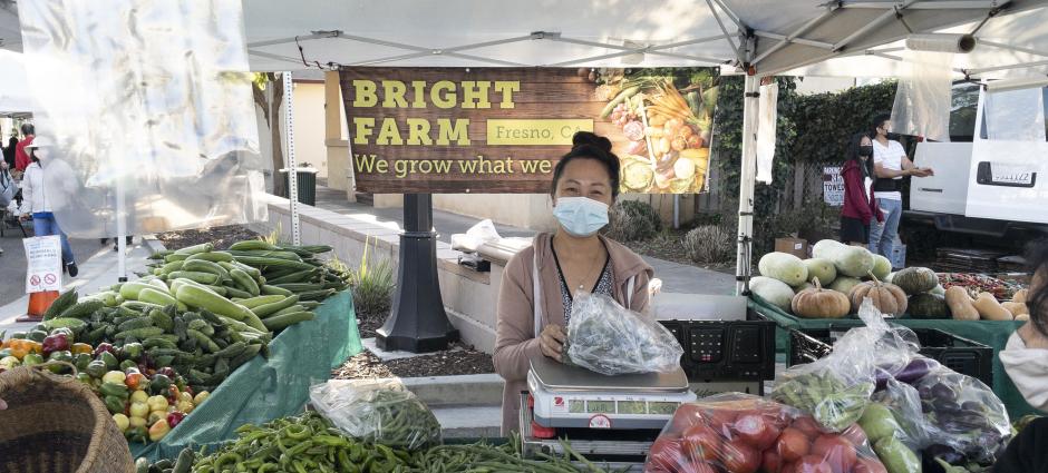 Bright Farm vendor behind table with various produce on display