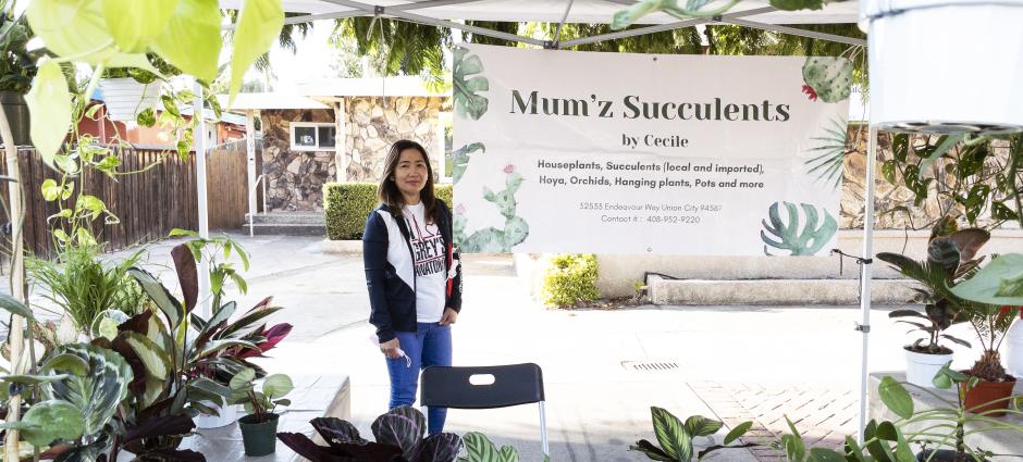 Mum'z Succulents vendor smiling behind display of succulents