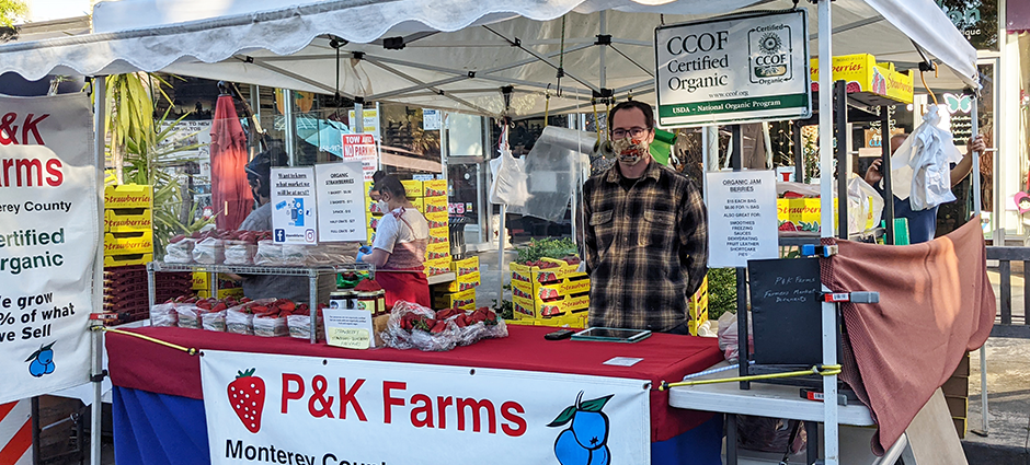 Worker stands behind booth full of berries.