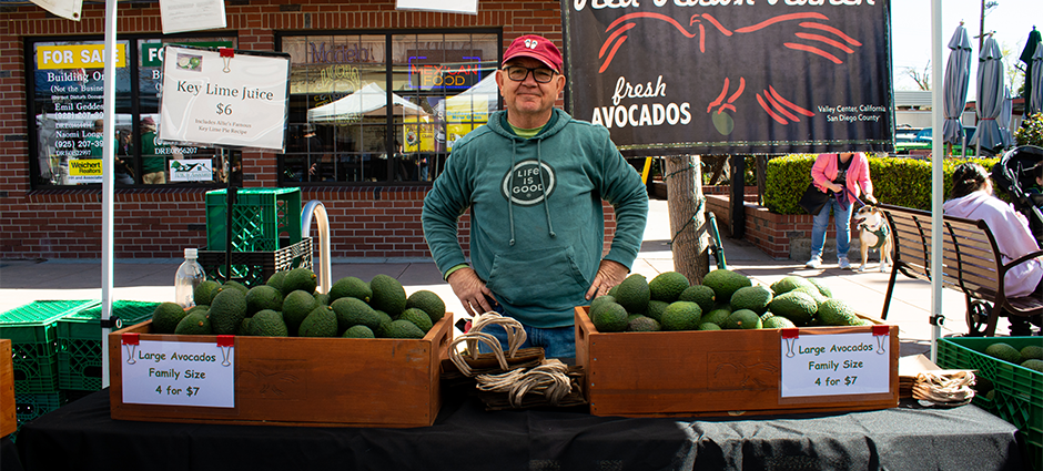 Producer smiling with hands on hips at stall in the farmers' market