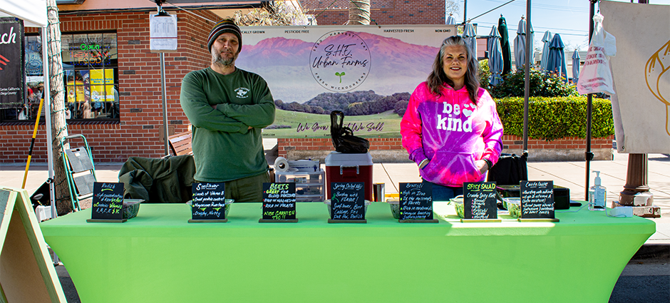 SHE Urban farms owners standing at their booth in the market