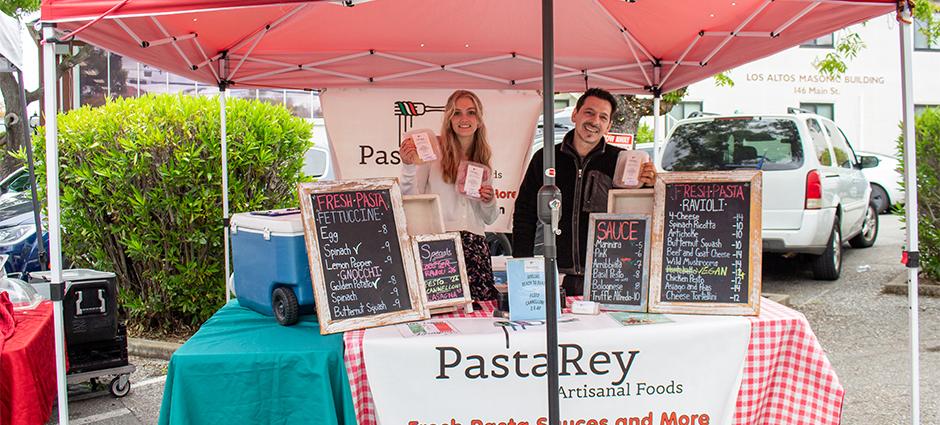 Smiling vendors at Pasta Rey holding their pastas