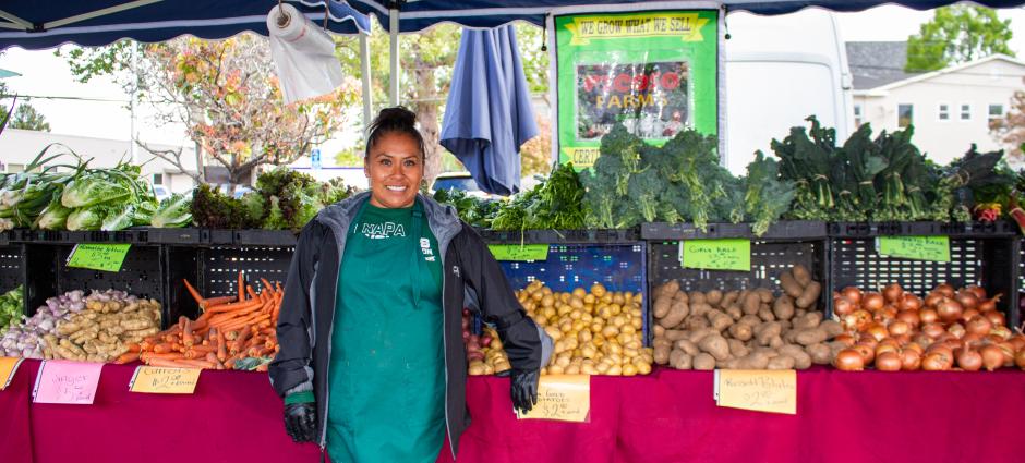 Photo of Nancy from Picoso Farm smiling in front of produce