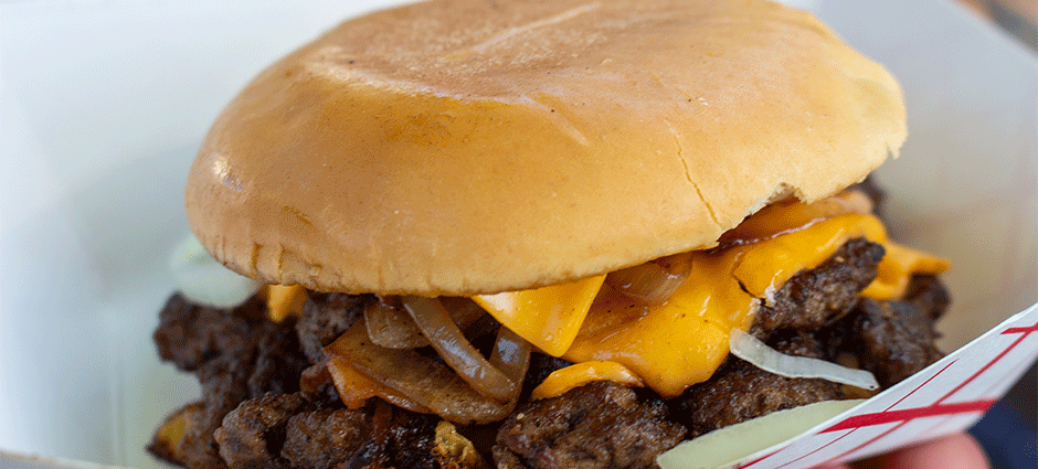 An Ace of Flavors burger being held by a hand at the Concord Thursday Farmers' Market