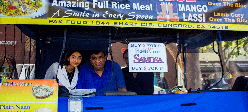 The father and daughter owners of Pak Food peeking through the window of their tent at Concord Thursday Farmers' Market