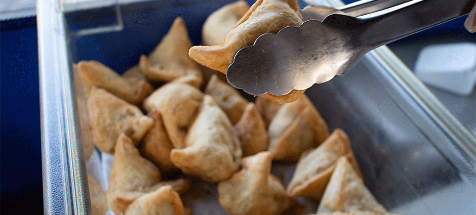 Pak Food Samosa being lifted with tongs 