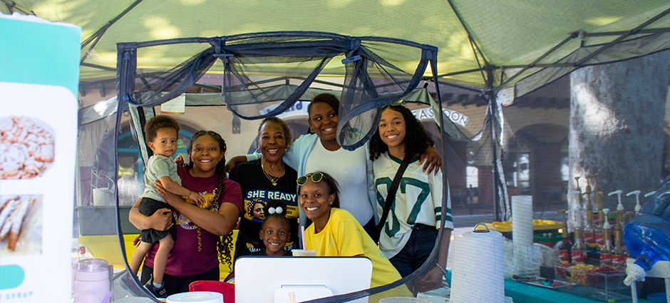 All the owners and their family peeking through the window of the Summer JAM Sweets stall at Concord Thursday Farmers' Market