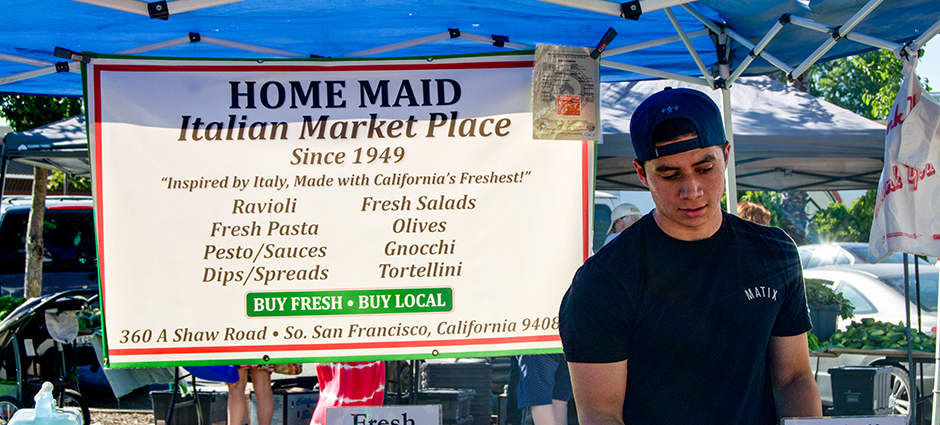 A man at the farmers' market in front of the Home Maid Ravioli booth